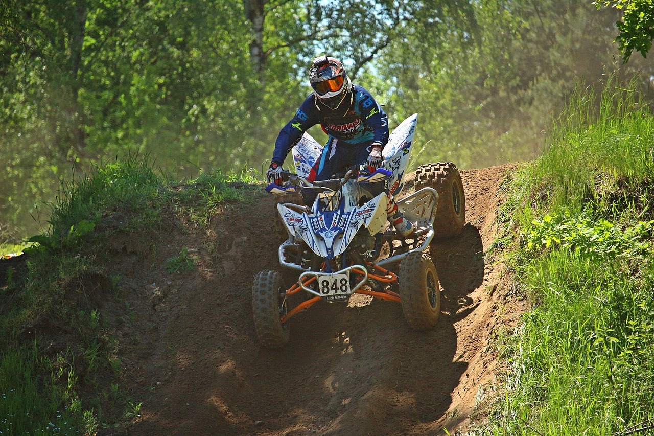 A man in bright gear driving an ATV in the forest
