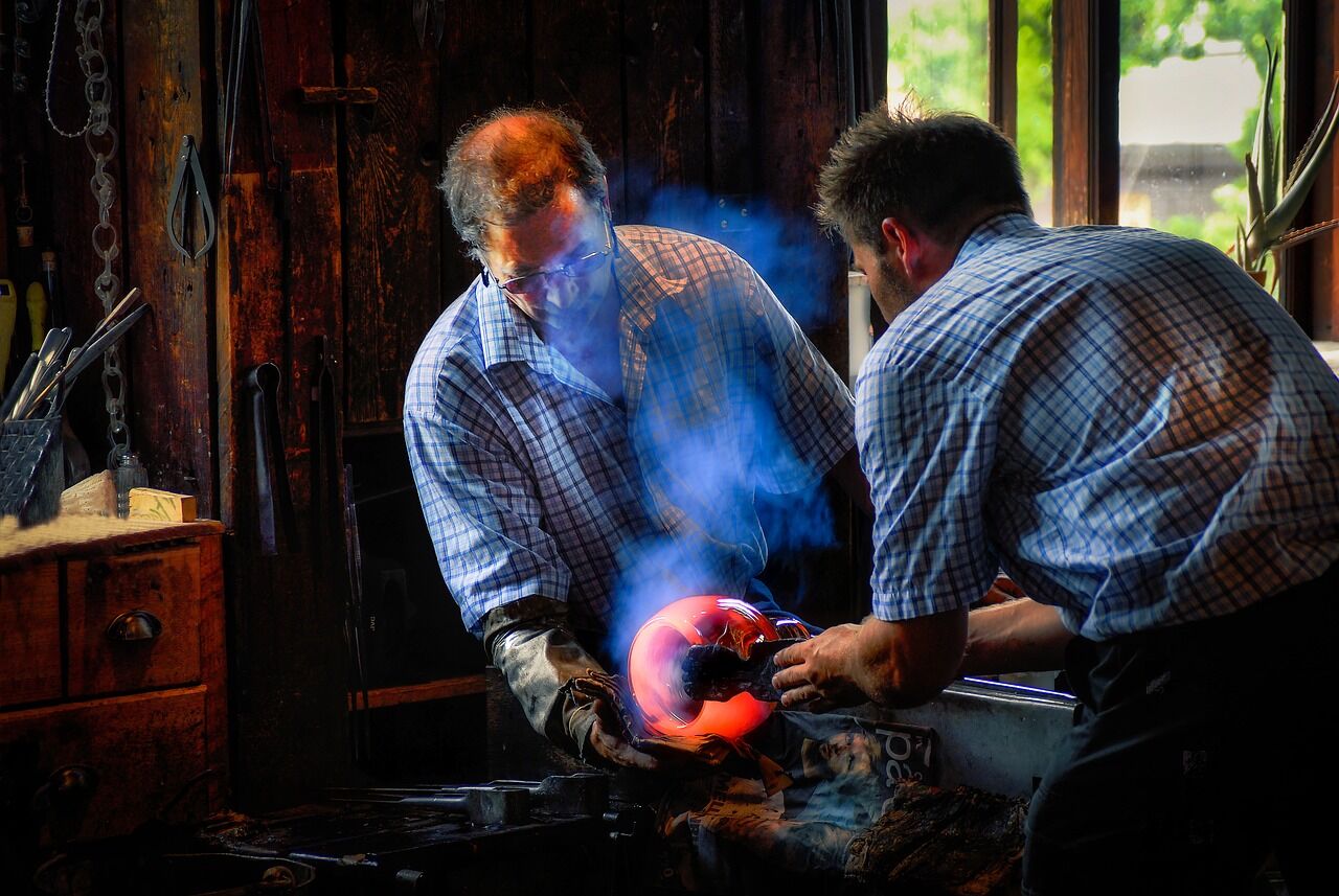 Two men handling molten glass