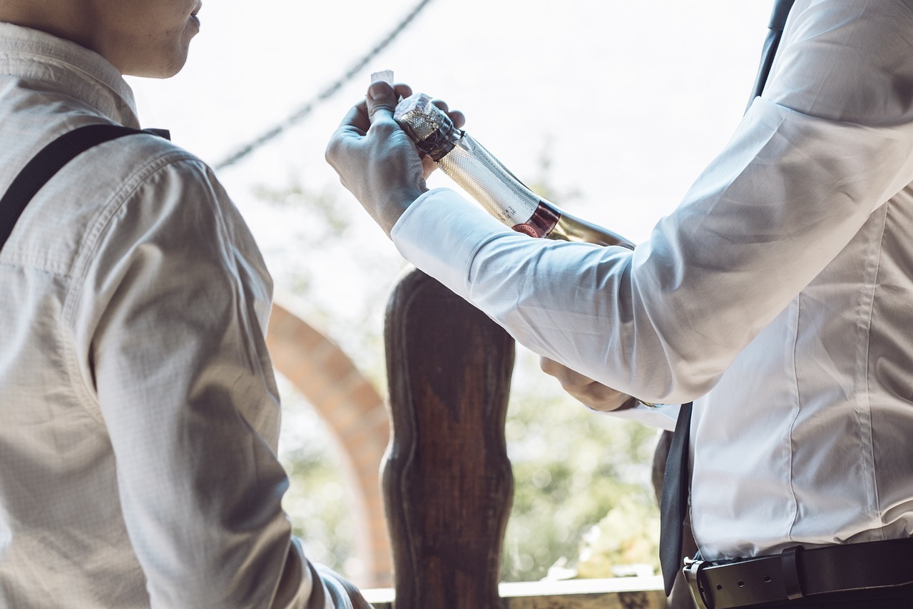 Two suited men preparing a wine bottle